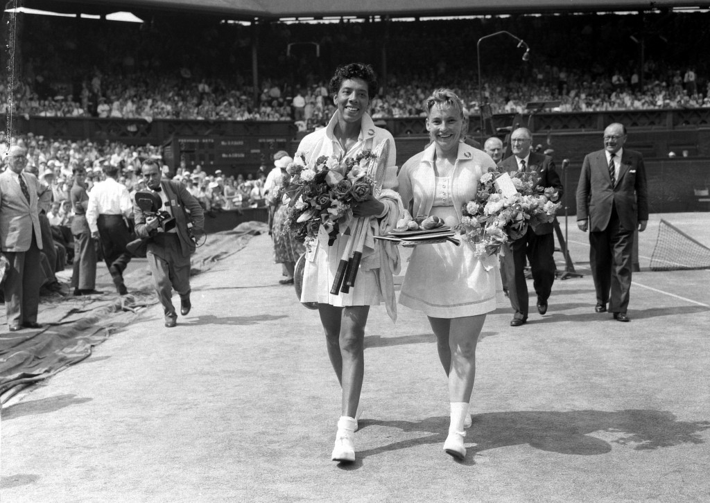Althea Gibson (USA) leaves Centre Court with Darlene Hard (USA) after beating her in the Ladies' Singles Final on Centre Court in straight sets - 6-3, 6-2, at The Championships 1957. They both carry flower bouquets. Held at The All England Lawn Tennis Club, Wimbledon. Credit: AELTC/Arthur Cole.